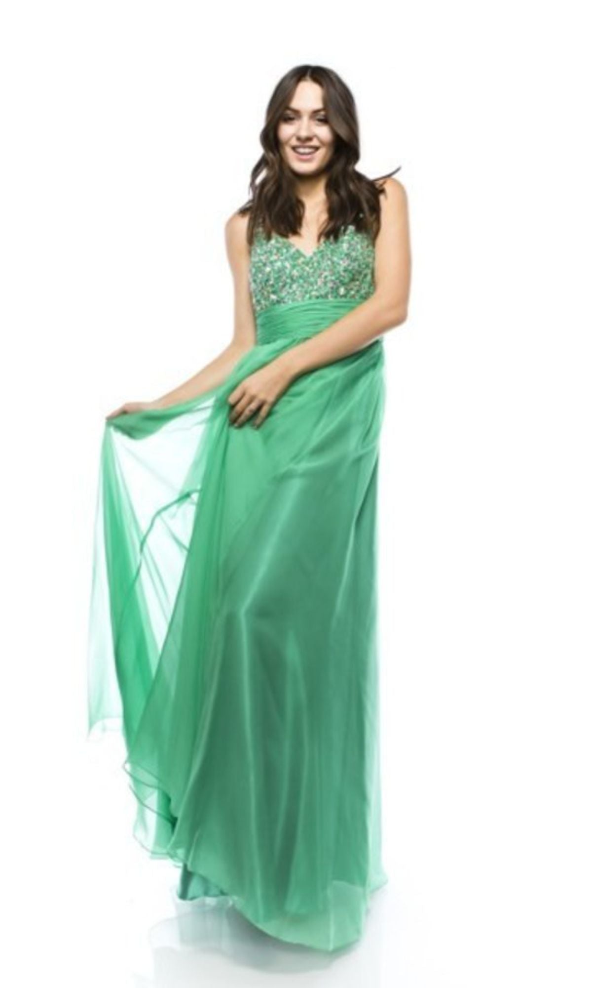 A woman in an affordable Empire-Waist Long Prom Dress: Chicas C7816 stands against a white background, holding out the skirt of her sleeveless green dress with a beaded bodice.